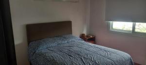 a bedroom with a bed with a blue comforter and a window at El Chalten hospedaje diario in General Pico