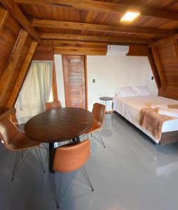 a bedroom with a bed and a wooden table and chairs at LIMMAT Chalés- Presidente Juscelino, MA in Morros +25 photos