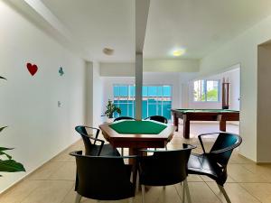 a dining room with a ping pong table and chairs at Apto em Barra Velha 340m da PRAIA com SACADA com CHURRASQUEIRA, AR CONDICIONADO WI-FI, PISCINA, PORTARIA 24h, ACADEMIA MINI MERCADO e vaga de GARAGEM in Barra Velha