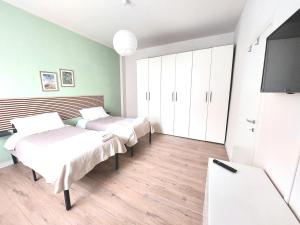 a room with two beds and a flat screen tv at Grazioso Bilocale in Busto Arsizio