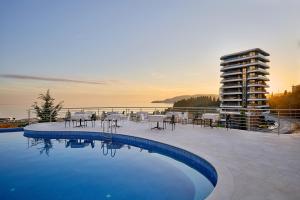 a swimming pool with chairs and a building in the background at Skyline Sunset in Bečići