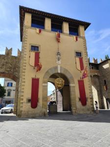 a building with an archway with red shutters on it at Du' passi dal centro in Arezzo