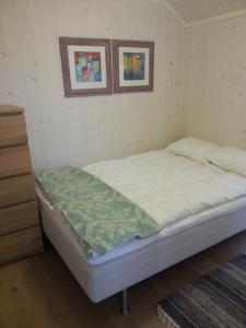 a bed in a room with two pictures on the wall at Moderne feriehus in Laupstad
