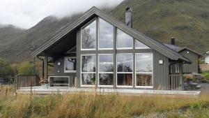 a house with large windows in front of a mountain at Moderne feriehus in Laupstad
