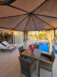 a patio with a table and chairs and a pool at Beach Villa mit Privatpool, Dachterrasse in Ma‘mūrah