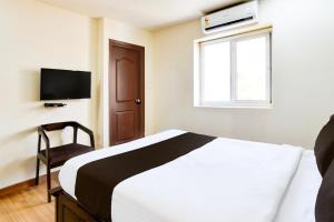 a bedroom with a bed and a tv and a window at Townhouse Gachibowli Near Gopichand Academy in Hyderabad