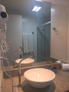 a bathroom with a sink and a shower with a camera at Farol Barra Flat completo e bem localizado in Salvador