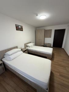 two beds in a room with wooden floors at Casa Drăghici in Nucet