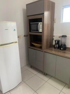 a kitchen with a microwave and a refrigerator at RCM Vilas - Casa confortável 1 in Joinville