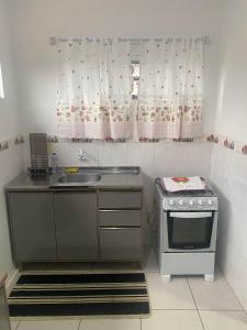 a small kitchen with a sink and a stove at RCM Vilas - Casa confortável 1 in Joinville +8 photos