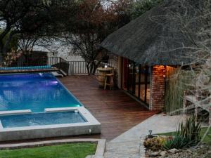 a backyard with a swimming pool and an umbrella at Cascata Lodge in Outjo