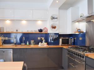 a kitchen with blue and white cabinets and a stove at Lapwing in Yarmouth