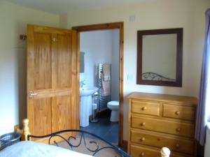 a bedroom with a dresser and a sink and a mirror at Tan Rallt Barn in Tregarth