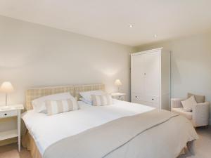 a bedroom with a large white bed and a chair at Hurworth - 25565 in Knapton