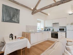 a kitchen and living room with a table and a couch at Hurworth - 25565 in Knapton