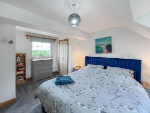 a bedroom with a blue bed and a window at Swinton Mill Farm Cottage in Duns +9 photos