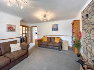 a living room with two couches and a stone wall at Swinton Mill Farm Cottage in Duns