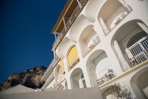 a white building with balconies and a mountain in the background at Tramonto d'Oro in Praiano