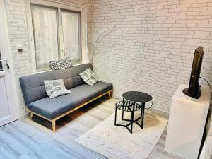 a couch sitting in a room next to a brick wall at Charmante maison triplexe avec jardinet in Orléans