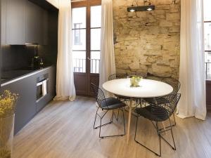 a table and chairs in a kitchen with a stone wall at Decô Apartments Barcelona-Born Apt. in Barcelona