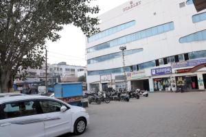 a white car parked in front of a building with motorcycles at Hotel Sky Blue in Surat +27 photos