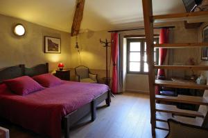 a bedroom with a bed with a red comforter at Des Lits Sur La Place in Hérépian