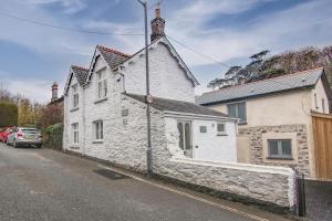 a white stone house on the side of a street at Rosevean Cottage St Agnes in St. Agnes