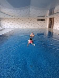 a man and a woman swimming in a swimming pool at Major Apartment in Dziwnów