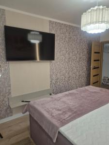 a bedroom with a flat screen tv on the wall at Major Apartment in Dziwnów