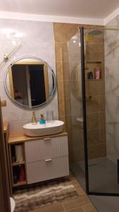 a bathroom with a sink and a shower with a mirror at Major Apartment in Dziwnów +1 photo