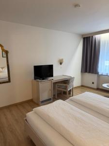 a hotel room with two beds and a desk with a television at Niederalteicher Hof in Hengersberg