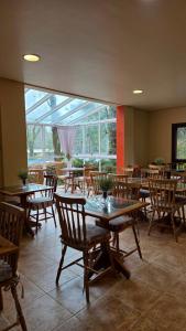 a restaurant with tables and chairs and a large window at Pousada Pinhão e Poesia in Canela