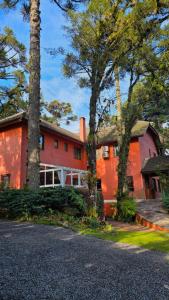 a red house with trees in front of it at Pousada Pinhão e Poesia in Canela