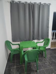 a green table and chairs in a room with a curtain at Xaveco hospedagem in Mangaratiba