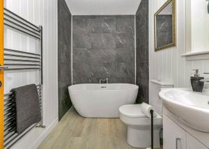 a bathroom with a tub and a toilet and a sink at Finest Retreats - Silverwood Junior Chalet in Errol +6 photos
