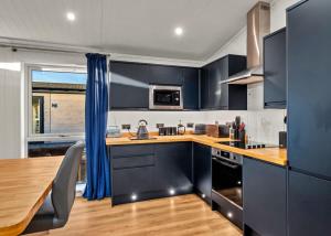 a kitchen with blue cabinets and a wooden table at Finest Retreats - Silverwood Premium Chalet in Errol