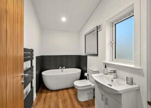 a bathroom with a tub and a toilet and a sink at Finest Retreats - Silverwood Premium Chalet in Errol +5 photos