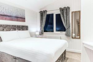 a white bedroom with a large bed and a window at Finest Retreats - Silverwood Spa Lodge in Errol