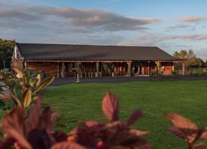 a large log cabin with a grass field in front of it at Finest Retreats - Silverwood Spa Lodge in Errol