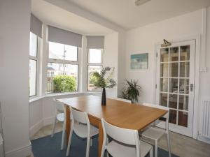 a dining room with a wooden table and white chairs at Angorfa Apartment in Pwllheli