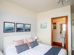 a bedroom with a white bed with pink and blue pillows at Angorfa Apartment in Pwllheli