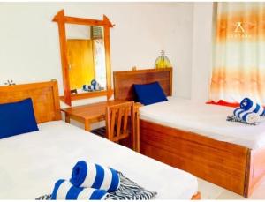 a bedroom with two beds and a table and a mirror at Happy Laugh Ella in Ella