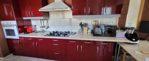 a kitchen with red cabinets and a stove top oven at Mafadel in Cluny