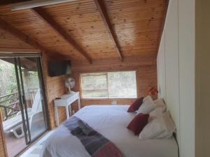 a bedroom with a large bed in a room with wooden ceilings at Log Cabin- Forest, Lagoon Sea location in Hermanus