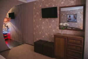 a room with a television and a dresser with a mirror at Hotel Yunost in Yekaterinburg