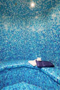 a blue tiled shower with a seat with a towel at Château de Bissieux in Châtillon-sur-Chalaronne