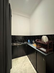 a kitchen with black cabinets and a sink at The Rosemary House in Weligama