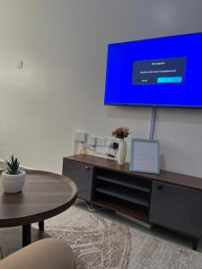 a living room with a table and a tv on a wall at Ems Haven Apartment in Ongata Rongai 