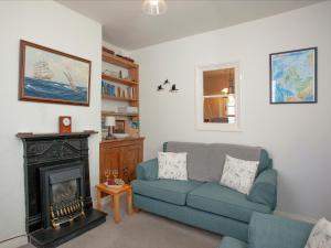 a living room with a blue couch and a fireplace at Tillerman Cottage Appledore Devon in Appledore