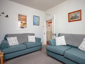 a living room with two blue couches and a window at Tillerman Cottage Appledore Devon in Appledore